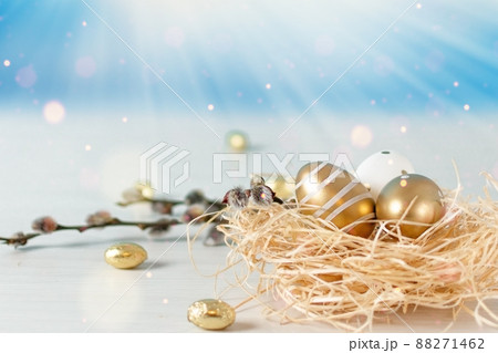 Golden colored Easter eggs in a nest on white wooden table over sky background. Happy Easter time. Golden colored Easter eggs in a nest on white wooden table over sky background. Happy Easter time. 88271462