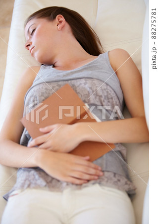 Books help her sleep. A young woman fast asleep on the couch with a book on her lap. Books help her sleep. A young woman fast asleep on the couch with a book on her lap. 88275781