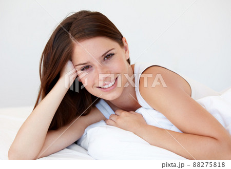 Enjoying sleeping in while on holiday. A gorgeous young woman smiling while lying in bed. Enjoying sleeping in while on holiday. A gorgeous young woman smiling while lying in bed. 88275818