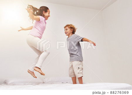 How high can you go. Shot of two little children jumping on a bed. 88276369