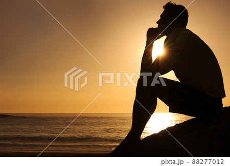 Searching for lifes answers. Silhouette of a thoughtful man sitting by the ocean - copyspace. Searching for lifes answers. Silhouette of a thoughtful man sitting by the ocean - copyspace. 88277012