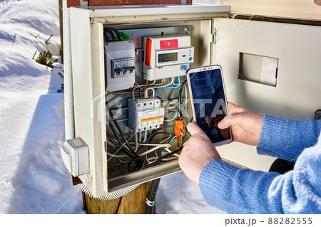Taking readings from external electric meter and making picture by phone outdoors. Taking readings from external electric meter and making picture by phone outdoors. 88282555