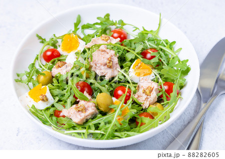 Salad with tuna, arugula, tomatoes, olives and eggs in a white plate. A traditional dish. Close-up. Salad with tuna, arugula, tomatoes, olives and eggs in a white plate. A traditional dish. Close-up. 88282605