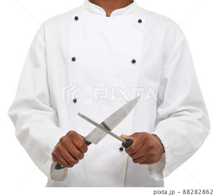Tools of the trade. A young chef sharpening his knives while isolated on a white background. Tools of the trade. A young chef sharpening his knives while isolated on a white background. 88282862