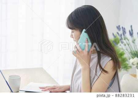 女性 スマホ 電話する パソコン リビング 女性 スマホ 電話する パソコン リビング 88283231