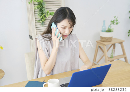 女性 スマホ 電話する パソコン リビング 女性 スマホ 電話する パソコン リビング 88283232