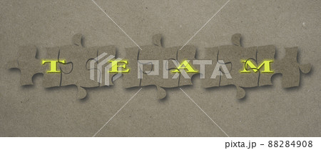 Team word assembled on puzzle pieces against a craft paper background. 88284908