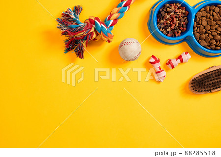 Toys -multi coloured rope, ball and dry food. Accessories for play on yellow background top view 88285518
