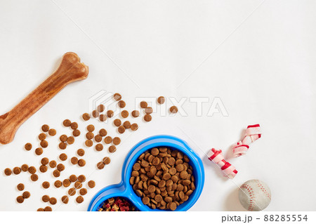 Dry pet food in bowl with a ball and dog bone on white background top view 88285554