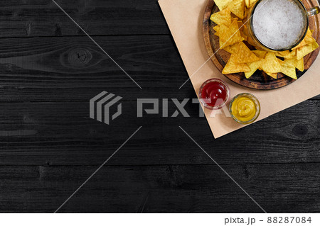 Glass of beer with nachos chips on a wooden background. Glass of beer with nachos chips on a wooden background. 88287084
