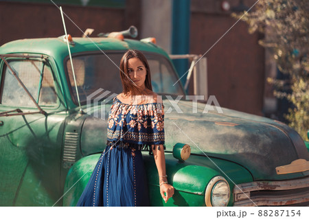 Beautiful young woman posing near green vintage car Beautiful young woman posing near green vintage car 88287154
