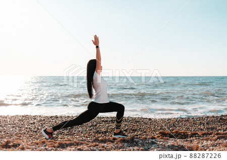 The concept of yoga and outdoor sports. A young woman doing yoga on a rocky beach. Copy space The concept of yoga and outdoor sports. A young woman doing yoga on a rocky beach. Copy space 88287226