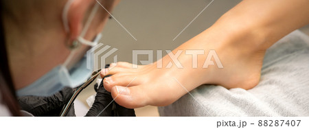 Pedicure master using nail nippers while trimming toenails in a pedicure salon Pedicure master using nail nippers while trimming toenails in a pedicure salon 88287407