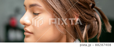 Portrait of a sensual young caucasian woman with closed eyes showing makeup tan on her face and hairstyle in a beauty salon Portrait of a sensual young caucasian woman with closed eyes showing makeup tan on her face and hairstyle in a beauty salon 88287408