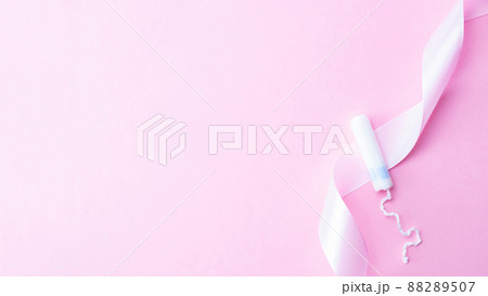 Tampon woman feminine hygiene. Pink ribbon with menstrual tampon on pink background. Menstruation feminine period. Soft tender protection for women critical days. 88289507