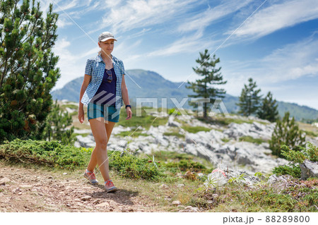 Young woman walking on trail in mountains on her summer vacation in europe Young woman walking on trail in mountains on her summer vacation in europe 88289800