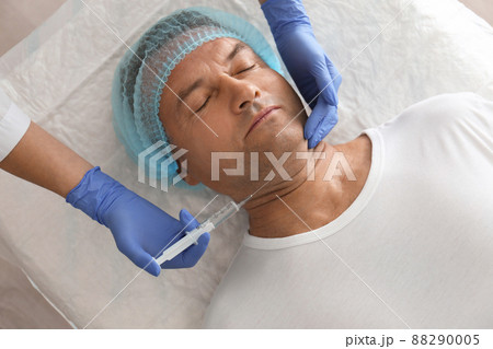 Mature man with double chin receiving injection in clinic, above view 88290005