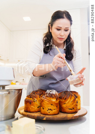 a female cook lubricates with melted butter a Kraffin, easter cake 88290488