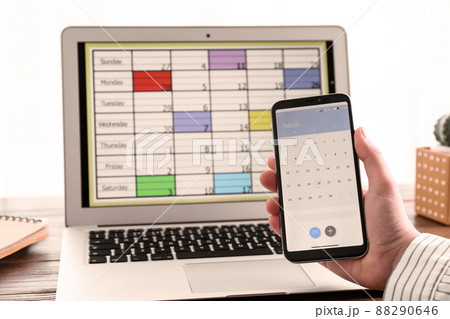 Woman holding smartphone with calendar app at table, closeup Woman holding smartphone with calendar app at table, closeup 88290646
