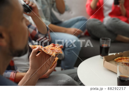 Man eating pizza with friends indoors, closeup Man eating pizza with friends indoors, closeup 88292257