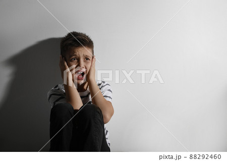 Scared little boy closing his ears near white wall, space for text. Domestic violence concept Scared little boy closing his ears near white wall, space for text. Domestic violence concept 88292460