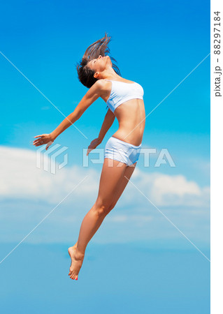 Propelled by an energy boost. A young woman in mid-air with her body outstretched. 88297184