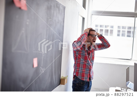 Sometimes you just have to let it out. Shot of young designer in his office, holding his head and screaming with frustration. 88297521