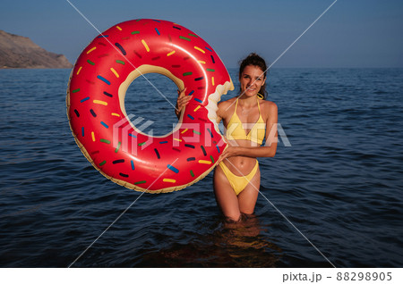 happy girl with a sexy body in a swimsuit with an inflatable circle in her hands is resting on the sea happy girl with a sexy body in a swimsuit with an inflatable circle in her hands is resting on the sea 88298905