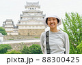 Happy Asian woman smiling with Himeji castle background. A female tourist is smiling and looking at camera in casually standing outdoor on a spring day. 88300425