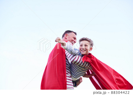 Into the wild blue yonder. Shot of a father and his young son pretending to be superheroes while playing outdoors. 88304422