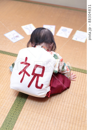 1歳の誕生日に袴を着て一升餅を背負って選び取りをする子供 88304831