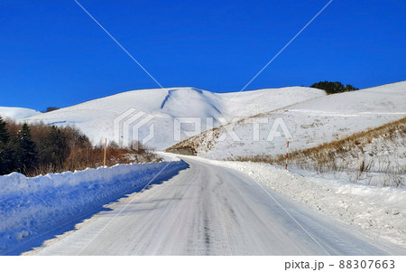 雪庇のできた雪山と除雪された道路(霧ヶ峰) 88307663