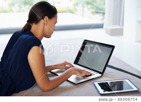 Working it out with the right tools. Shot of an attractive young woman using her laptop and tablet while relaxing on the floor at home. Working it out with the right tools. Shot of an attractive young woman using her laptop and tablet while relaxing on the floor at home. 88309754