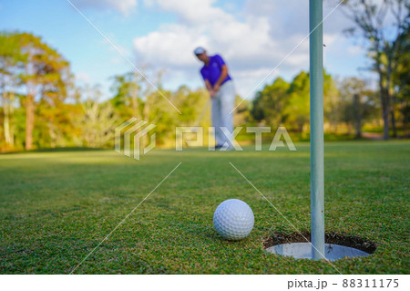 Golfer action to win after long putting golf ball on the green golf, lens flare on sun set evening time. 88311175