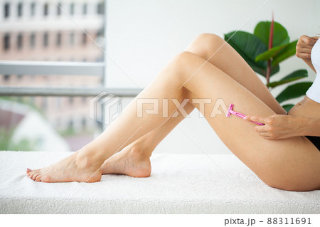 Woman is holding a razor in his hand and shave her legs. Woman is holding a razor in his hand and shave her legs. 88311691