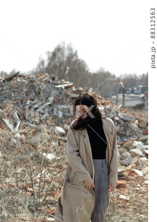 A lonely girl in a coat and jeans on the ruins of a ruined house. consequences of the war grain effect A lonely girl in a coat and jeans on the ruins of a ruined house. consequences of the war grain effect 88312563