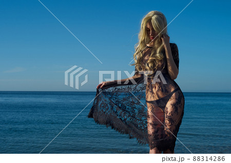 A woman in a patterned black dress on the beach. A woman in a patterned black dress on the beach. 88314286