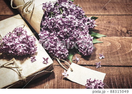 Gift and bouquet of lilacs on a wooden table 88315049