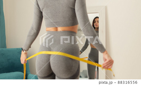 Fitness Woman Measuring butt With Tape at home. strong buttocks concept. Fitness Woman Measuring butt With Tape at home. strong buttocks concept. 88316556