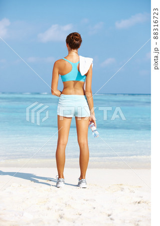 Relaxation after workout. Rear view of fit young woman standing while facing ocean. 88316723