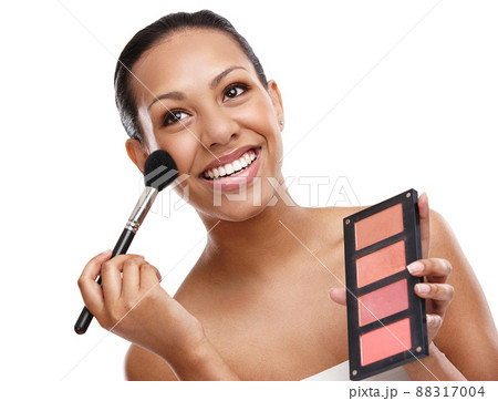 Leave a little sparkle wherever you go. Cropped shot of a beautiful young woman applying blush to her face while standing in studio-isolated on white. 88317004