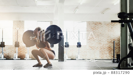 Stay sexy, squat often. Full length shot of an attractive young woman lifting weights in the gym. 88317290