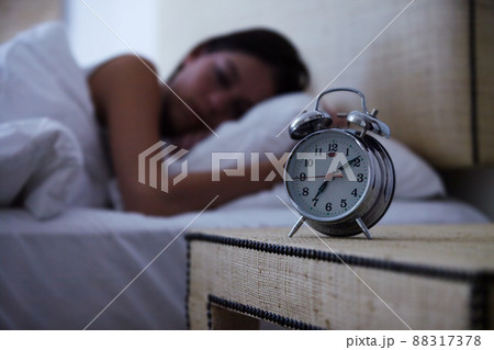 Sleeping the day away. A young woman sleeping with her alarm clock next to her bed. Sleeping the day away. A young woman sleeping with her alarm clock next to her bed. 88317378
