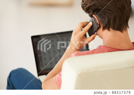 Taking full advantage of the convenience that wireless technolog. Rear-view of a young man talking on his mobile while using his laptop. 88317379