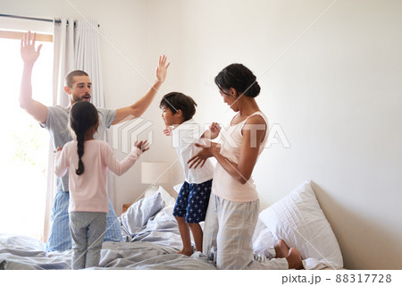 The fun never stops in our house. Shot of a beautiful young family of four having fun and spending time together in their bedroom at home. 88317728