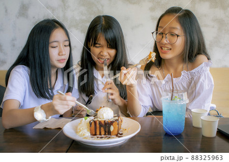 group of asian teenager eating sweet snack in coffee cafe group of asian teenager eating sweet snack in coffee cafe 88325963