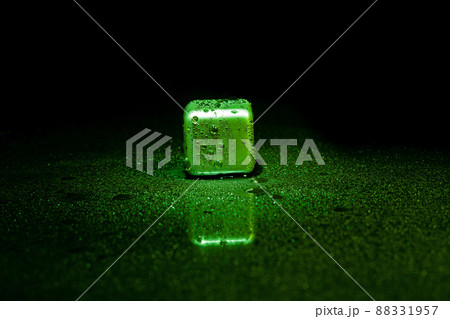 Green stainless steel cubes simulating ice for cooling drinks on a black surface with a reflection. 88331957
