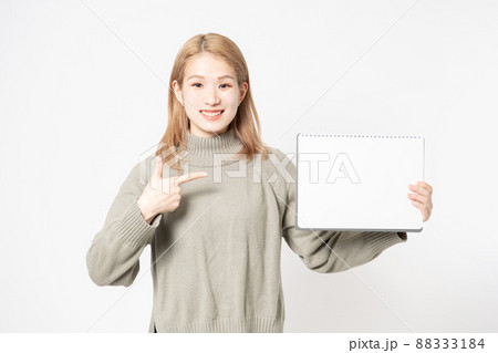 白い背景の前に立って小さいスケッチブックを見せている若い女性 白い背景の前に立って小さいスケッチブックを見せている若い女性 88333184
