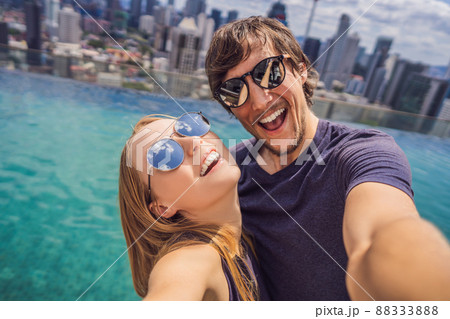 young happy and attractive playful couple taking selfie picture together at luxury urban hotel infinity pool and panoramic view of the city enjoying holidays honeymoon travel in diversity ethnicity young happy and attractive playful couple taking selfie picture together at luxury urban hotel infinity pool and panoramic view of the city enjoying holidays honeymoon travel in diversity ethnicity 88333888