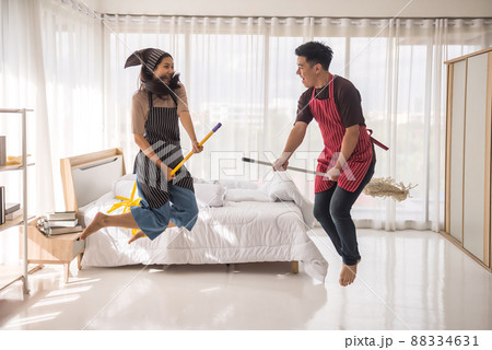 Asian young couple jump and ride broomstick and yellow mop Asian young couple jump and ride broomstick and yellow mop 88334631